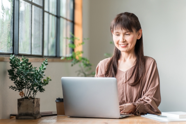 笑顔の主婦がパソコンで副業をして笑みを浮かべている
